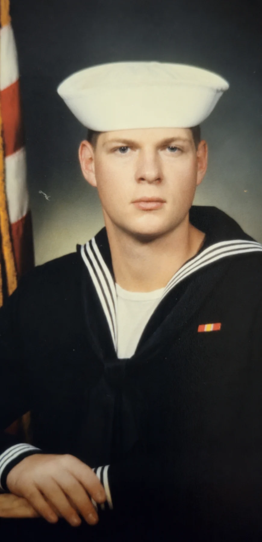 Jerry Ondo in his United States Navy dress uniform, an American flag behind him.
